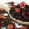 Black tea with cranberries and raspberries on a wooden spoon