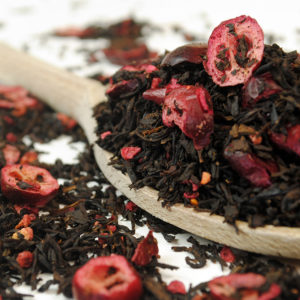 Black tea with cranberries and raspberries on a wooden spoon